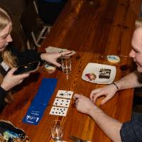 Two people at event sitting at table and playing a card game